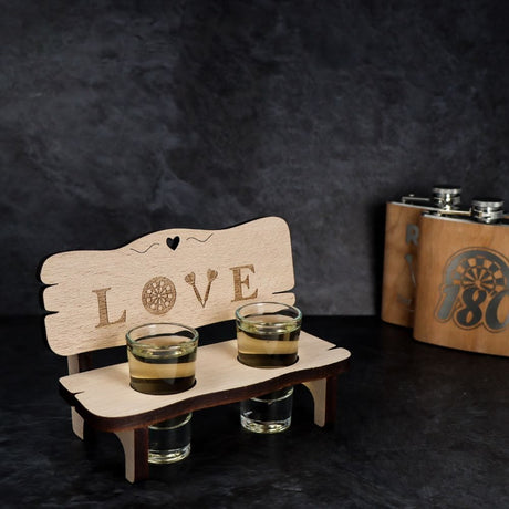 Holzbank mit zwei Schnapsgläsern und dem Schriftzug Love auf der Rückenlehne